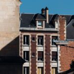 Historic brick and stone buildings under clear blue sky in Amiens, France.