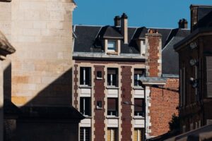 Historic brick and stone buildings under clear blue sky in Amiens, France.