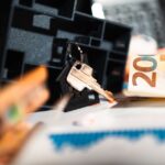 Keys with a house model, Euro bills, and charts suggesting real estate and financial themes.