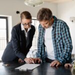 A family reviews real estate documents with an agent, signing for their new home.