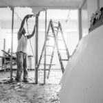 man in white t-shirt and black pants standing on ladder