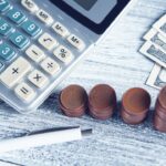 a calculator, pen, and money on a table